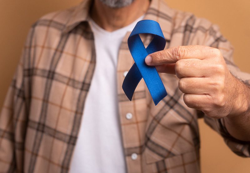 Man-holding-a-blue-ribbon-representing-prostate-cancer-awareness